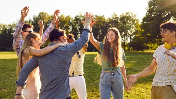 Cover image of teenagers high fiving on a lawn in the sun