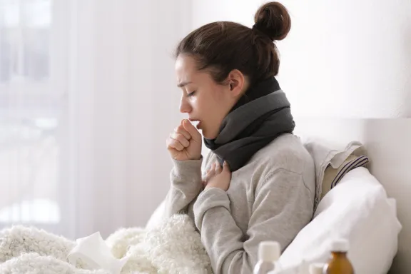 Image of a women in bed coughing