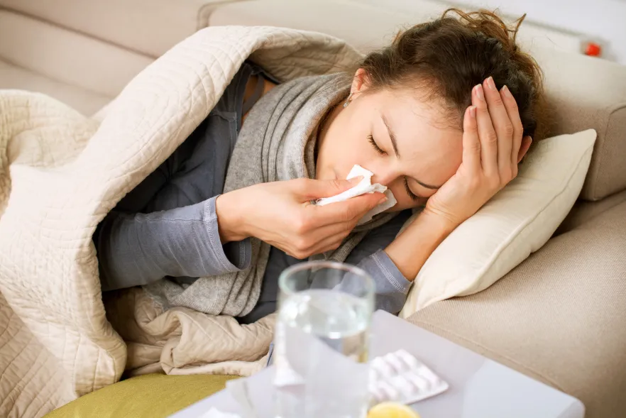 Image of a woman sneezing into a tissue