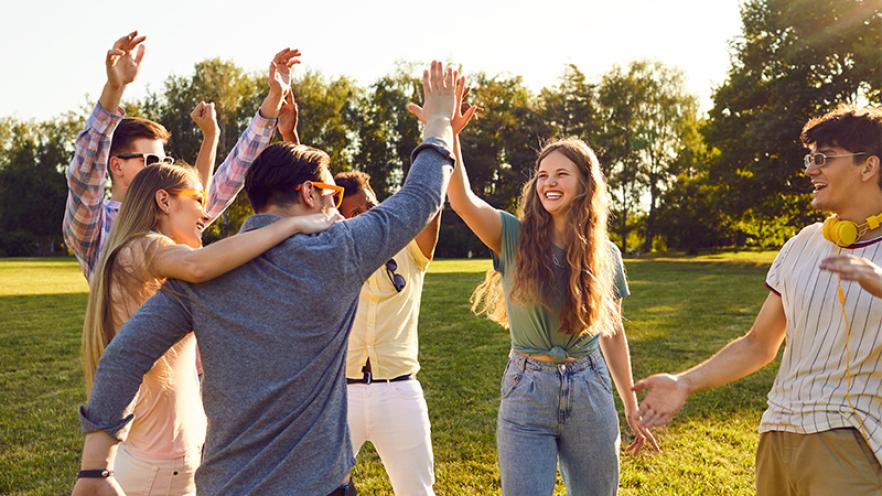 Cover image of teenagers high fiving on a lawn in the sun
