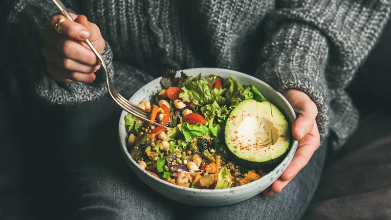 Image of 2 hands holding a salad and fork