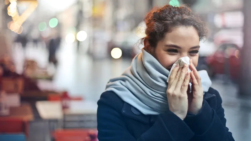 Woman blowing nose with tissue